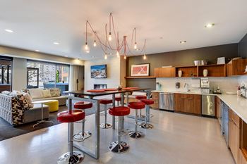 Clubroom with full kitchen, raised island and barstools and couches in front of fireplace